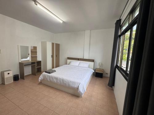 a bedroom with a bed and a desk and window at KataKeet in Kata Beach