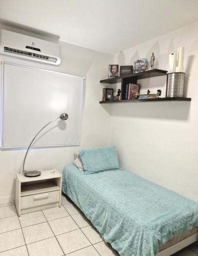a bedroom with a bed and a lamp on a night stand at Pacífico Guest House Recife - Polo Médico e Universidades in Recife