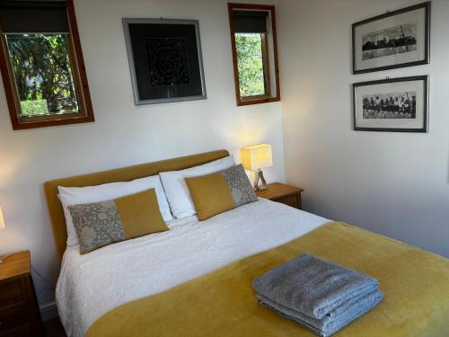 a bedroom with a bed and two windows at Chalet on the Green - Self Contained with parking. in Inshes