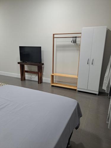 a bedroom with a bed and a tv and a mirror at Apartamentos casa da Lu 101 in Primavera do Leste