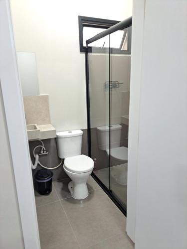 a bathroom with a toilet and a glass shower at Apartamentos casa da Lu 101 in Primavera do Leste