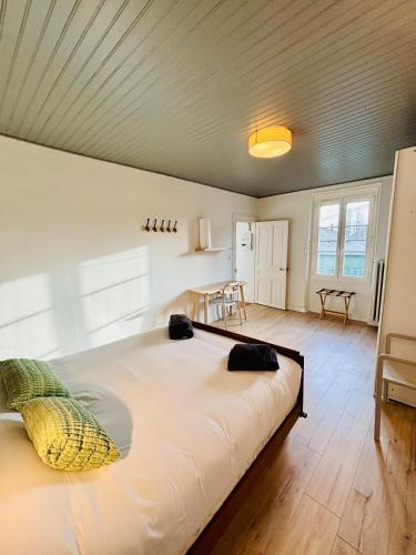 a large white bed in a room with a table at Le Clemenceau - Appartements meublés in Gien