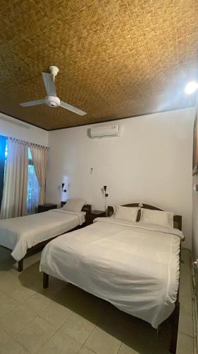 a bedroom with two beds and a ceiling at Rumah Saga in Gili Trawangan