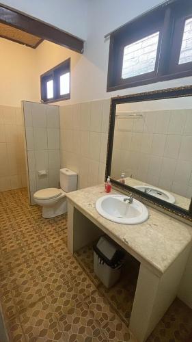 a bathroom with a sink and a toilet and a mirror at Rumah Saga in Gili Trawangan
