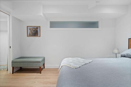 a white bedroom with a bed and a chair at Private Cedar Sauna Retreat - Kitchenette, King Bed, Spa Bath - Deep Cove in North Vancouver