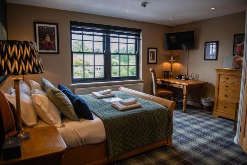 a bedroom with a bed with a desk and a window at Blue Bell Country Inn in Knaresborough
