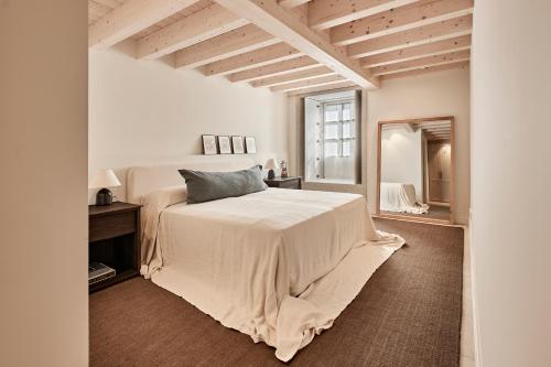 a white bedroom with a bed and a mirror at Casa Conde in Furelos