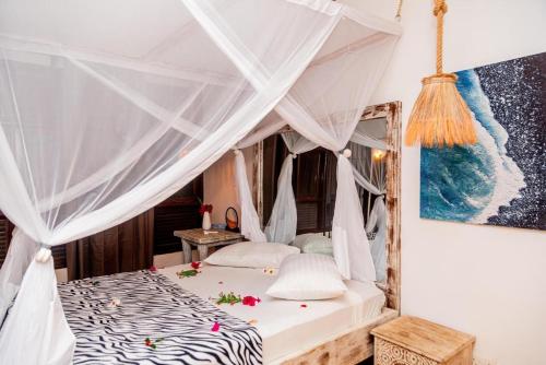 a bedroom with a bed with a canopy at BREEZEACARDEs in Diani Beach