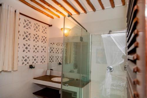 a bathroom with a glass shower and a sink at BREEZEACARDEs in Diani Beach