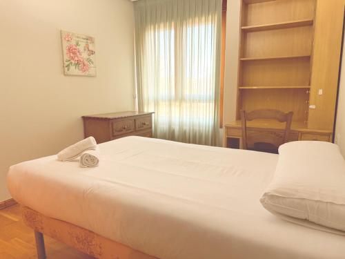 a bedroom with a bed and a chair and a window at Av Valladolid 45 in Soria