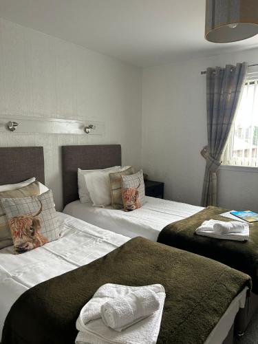 a hotel room with two beds with towels on them at Tay Villa in Inverness