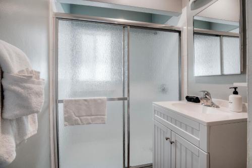 a white bathroom with a shower and a sink at Oceanfront Condo, Private Balcony, Beach Access, Sunset Views in Carlsbad