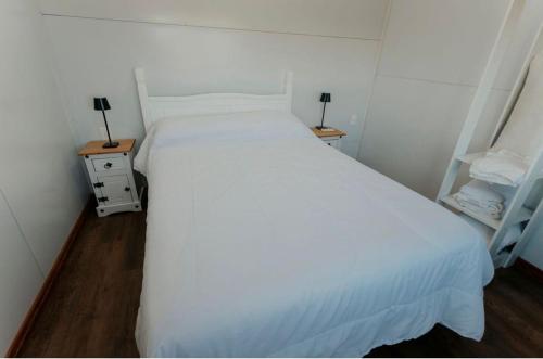 a large white bed in a room with two night stands at La Finca 2 in Mercedes