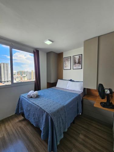 a bedroom with a bed with a blue blanket and a window at 200m metro bras com Piscina in São Paulo