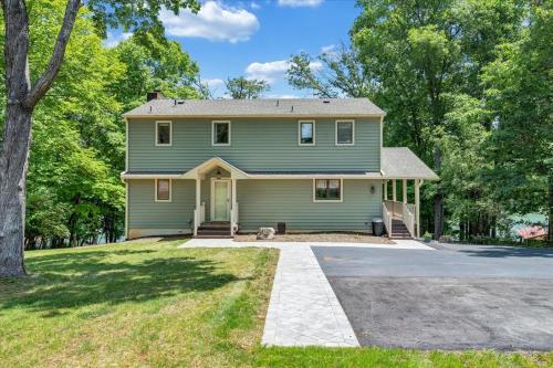 a green house with a dog in the driveway at Emerald Shores - Lakefront, Private Dock & Fire Pit in Moneta