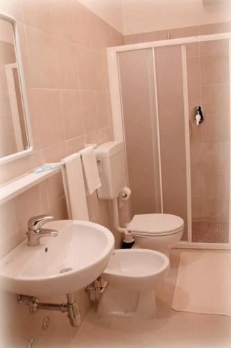 a white bathroom with a toilet and a sink at Hotel Bel Air Frontemare in Rimini
