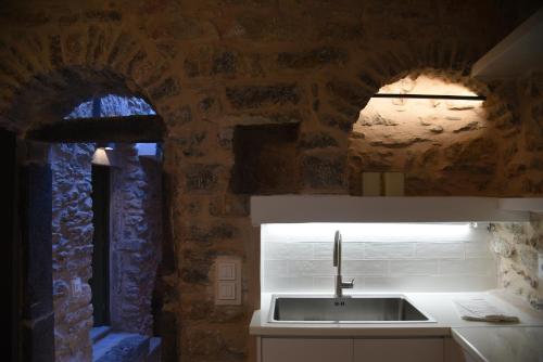 a kitchen with a sink and a stone wall at Armathia Accommodation in Mestá