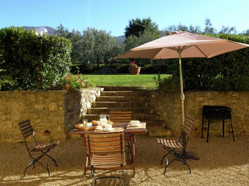 einen Tisch und Stühle mit Sonnenschirm im Hof in der Unterkunft Belvilla by OYO Podere Pulicciano Orciaia in Pian di Scò