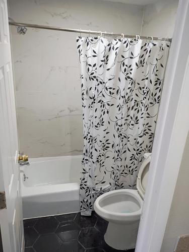a bathroom with a toilet and a black and white shower curtain at Bel Air Motor Lodge in Maple Shade