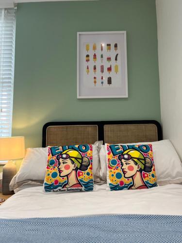 a bed with two colorful pillows on top of it at Ocean Reach in Porthcawl