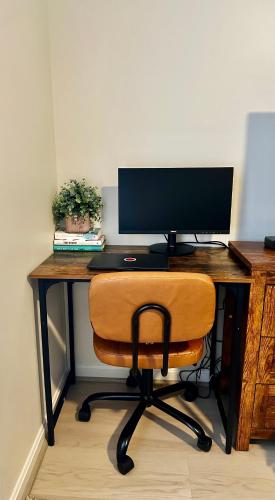 a wooden desk with a computer monitor and a chair at Modern and Comfy-2BR 2BA with pool access - ground floor, Near Outlets & Beaches in Rehoboth Beach