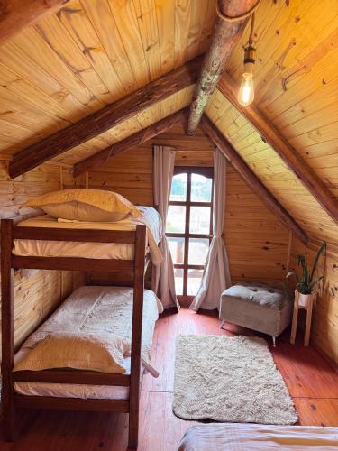 a bedroom with two bunk beds in a log cabin at Cabaña El Guayabo in Villa Urquiza