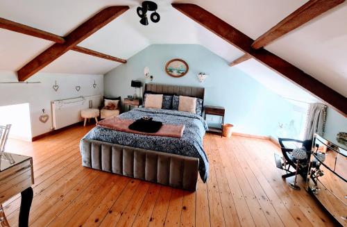 a bedroom with a large bed and wooden floors at Cute Quirky Cottage in Llandow