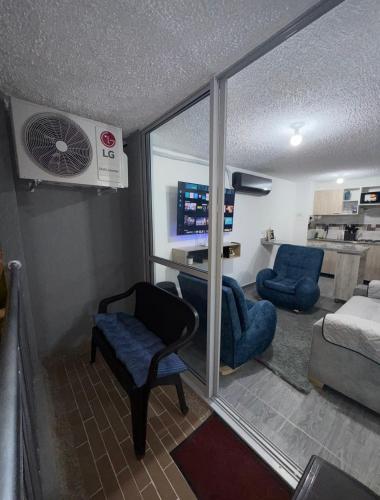 a room with a fan and two chairs and a living room at Apartamento exclusivo en ricaurte Cundinamarca in Ricaurte