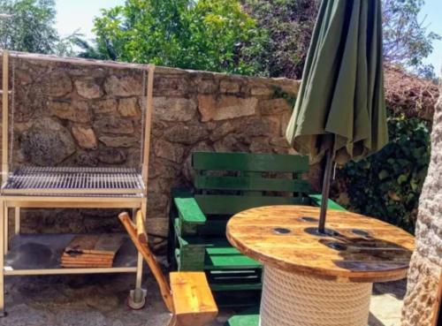 a table with an umbrella next to a stone wall at Casa Candy in Muxia