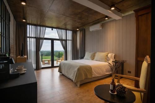 a bedroom with a bed and a table and a window at Casa Pradera - Hotel Serrano in Sierra de los Padres