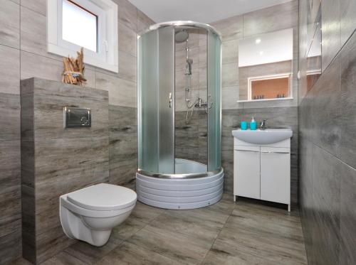 a bathroom with a shower and a toilet and a sink at Domki Agnes in Darłowo