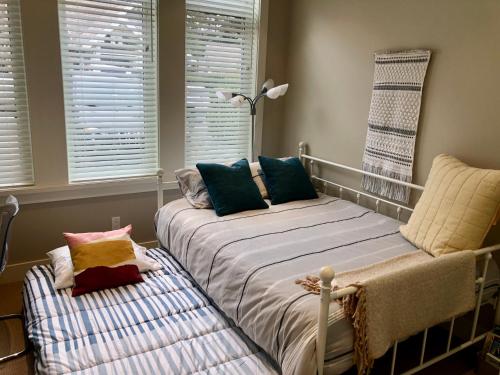 a bedroom with a bed and a chair and windows at Qualicum Landing Seaside Vill in Qualicum Beach