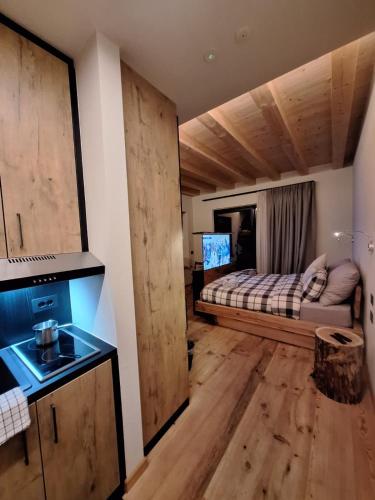 a room with a bed and a kitchen with wooden floors at Green Hospitality Monolocale Stella Alpina in Livigno