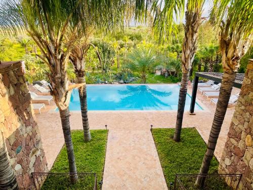 a swimming pool between two palm trees in a yard at Villa Malika Private Luxury Villa Marrakech in Tameslouht
