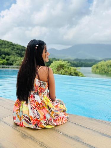 a woman in a dress sitting next to a pool at Serene Aqua Hills in Kozhikode