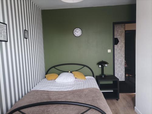 a bedroom with a bed with yellow pillows and a clock at chambre double in Poitiers