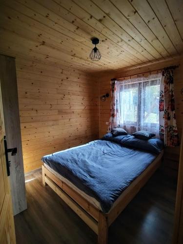 a bedroom with a bed in a wooden cabin at Domki Tepakówka in Wołkowyja