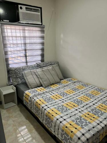 a bedroom with a bed with a comforter on it at Log Horizon by The Guild Oasis Transient House in Rosario