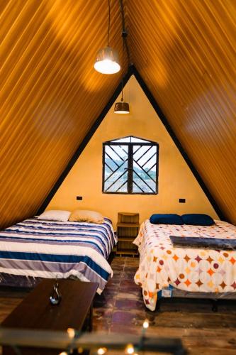 a attic room with two beds and a window at Casa Monte Bello- Cabaña privada in Huehuetenango