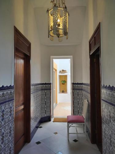 a hallway with a door and a chair and a chandelier at Casa MaCló Tranquilidad y autenticidad in Máguez