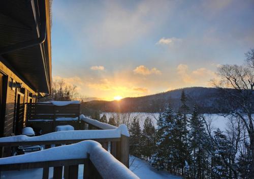 a snow covered balcony with the sunset in the background at 3306 Studio, Condo sur le Lac in Lac-Superieur