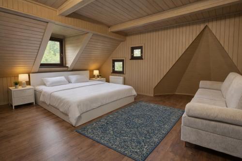 a bedroom with a large bed and a couch at Everwood Lodge, Transylvania in Sub Cetate