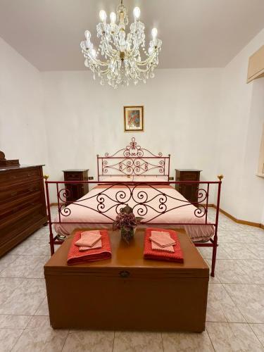 a bedroom with a bed with a table and a chandelier at House of Arcadia in Pistoia