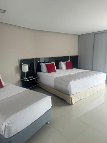 zwei Betten mit roten Kissen in einem Hotelzimmer in der Unterkunft Hotel Blue 66 in Cali