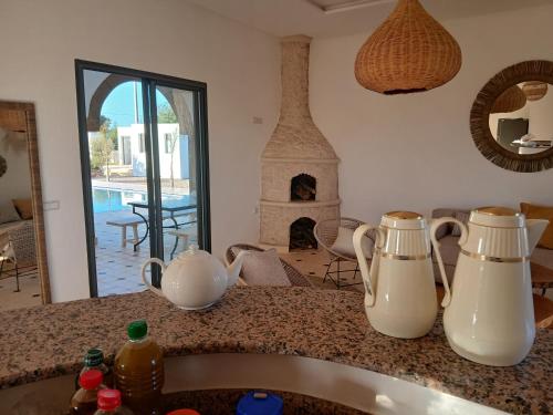 a kitchen with two milk pitchers on a counter with a fireplace at Chambres Maison d'hôtes MaisonBlanche in Essaouira
