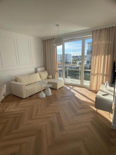 a living room with a white couch and a large window at Apartamenty Sady in Słubice