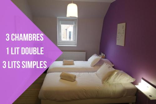 two beds in a hotel room with purple walls at La Maison Saint-Pry in Béthune