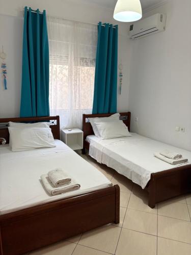 deux lits dans une chambre avec des rideaux bleus dans l'établissement Blanche appartement, à Saranda
