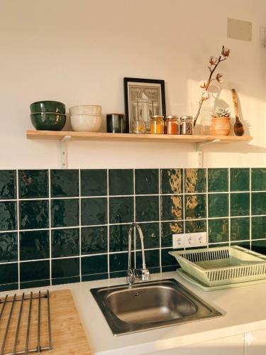a kitchen with a sink and a green tiled wall at Apartamento Gades Conil C in Conil de la Frontera