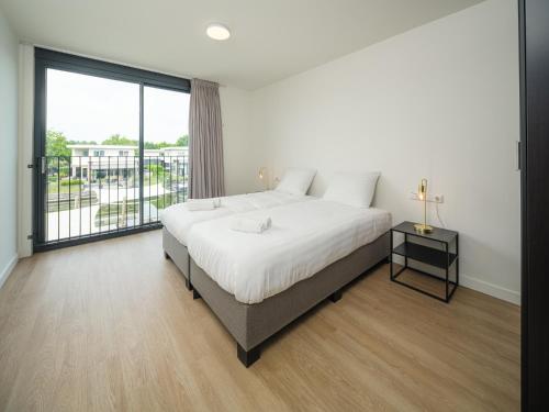 a bedroom with a large bed and a large window at Harderwold Villa - 228 in Zeewolde